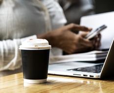 plastic cup at African woman with smartphone and notebook