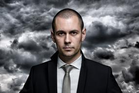 Portrait of serious caucasian man in Tie Suit at clouds