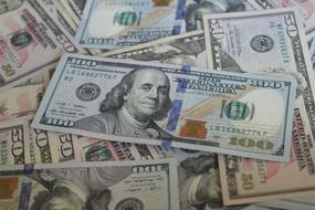 hundred us dollars bill over pile of banknotes