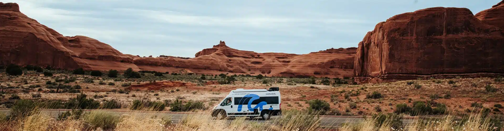 roadsurfer campervan in the usa driving through a red stone landscape 