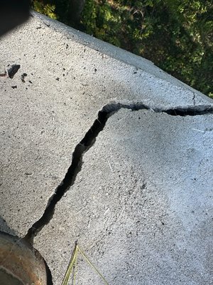 Photo of Cornerstone Custom Brick - Fraser, MI, US. The crack on our less than 6 month old chimney cap, caused by wood planks that were used to support PART of the cap