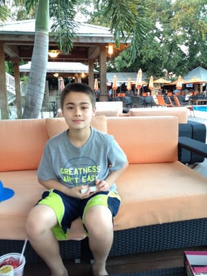 Photo of Osprey Beach Tiki Bar and Grille - Osprey, FL, US. a boy sitting on a couch