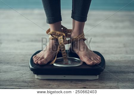 Close Up. Young Woman Standing On Weigher On Floor. Diet Concept. Weight Loss Problem. Starving Youn