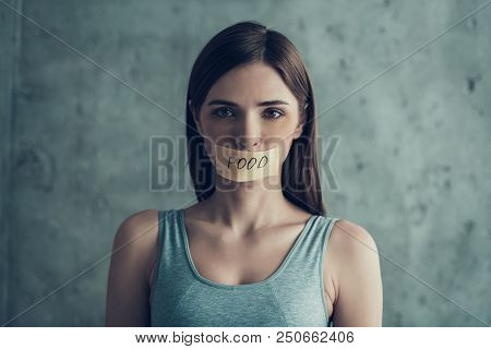 Young Woman With Taped Mouth With Word Food. Diet Concept. Weight Loss Problem. Starving Young Woman