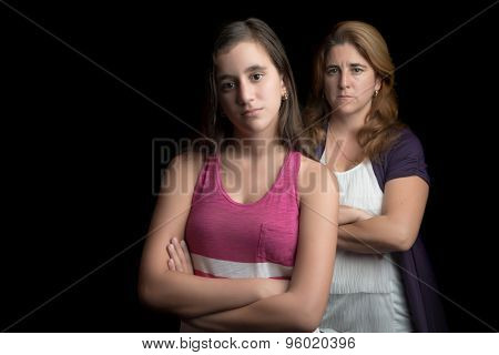 Teenage girl and her mother sad and angry at each other isolated on black