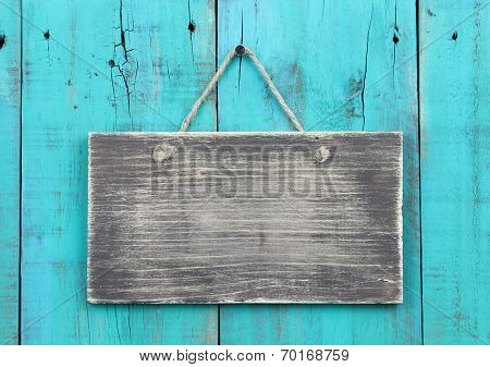 Blank rustic sign hanging on antique teal blue distressed fence