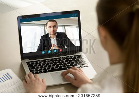 Businesswoman calling businessman online by video chat computer app, partners negotiating online on virtual meeting, employee reporting to boss running business remotely, close up rear view