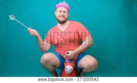 A Youna Young Bearded Freaky Man In A Pink T-shirt With A Diadem On His Head Riding A Unicorn With A