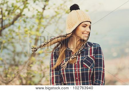 Young woman in plaid shirt and knitted hat in autumn