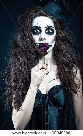 Young Woman In The Image Of Sad Gothic Freak Clown Holds Withered Flower