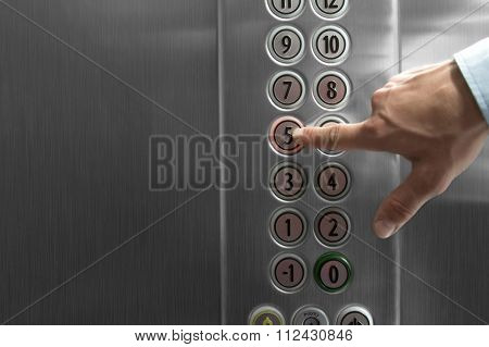 Forefinger pressing the fifth floor button in the elevator