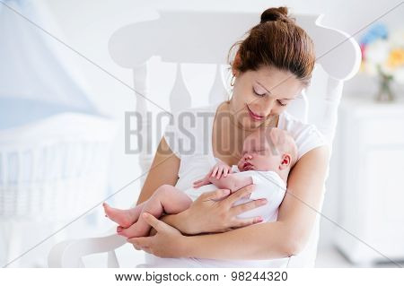 Young Mother And Newborn Baby In White Bedroom