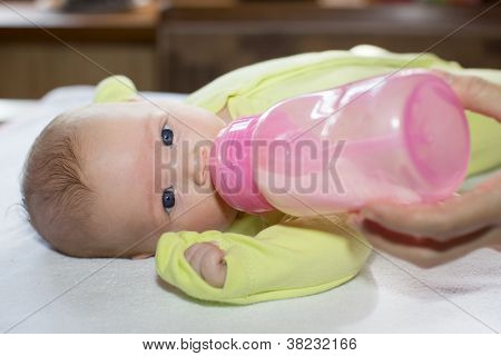 Newborn Baby Girl With A Bottle Of Milk. The Concept Of Food And Parenting