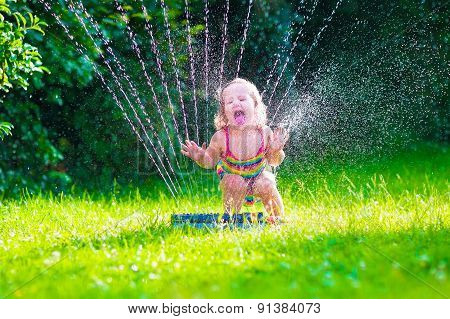 Little Girl Playing With Garden Water Sprinkler