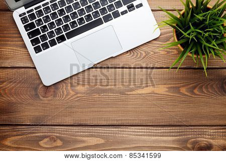 Office desk table with laptop computer and flower. Top view with copy space