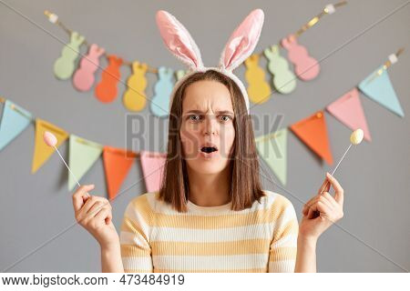 Portrait Of Shocked Scared Surprised Woman Wearing Striped Shirt Celebrating Easter Isolated Over Gr