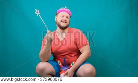 A Youna Young Bearded Freaky Man In A Pink T-shirt With A Diadem On His Head Riding A Unicorn With A