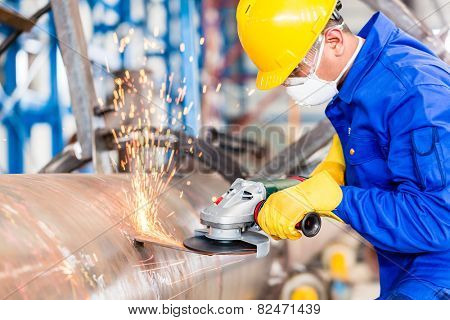 Industrial worker in manufacturing plant grinding to finish a pipeline