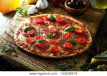 Fresh italian pizza on wood. Pizza with cheese salami and tomatoes. Fast food. Rustic pizza