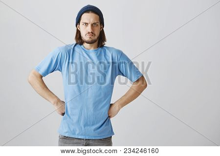 Grumpy Guy Is Angry And Disappointed. Portrait Of Funny Furious Guy With Long Hair And Beard In Blue