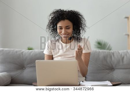 African Woman Wearing Headphones With Microphone Chatting Online Using Webcam