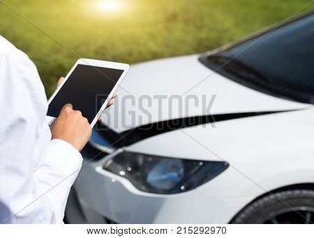 Insurance agent inspecting damaged car with insurance claim form on digital tablet