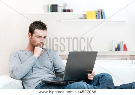 Young man working absorbed on laptop at home copy space