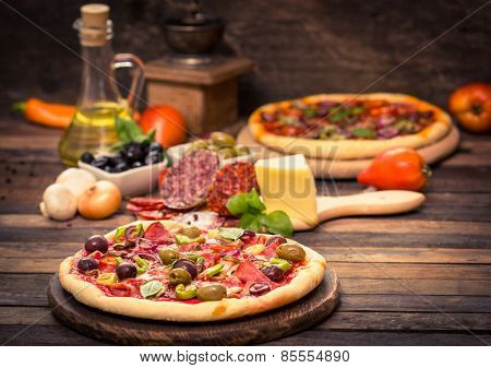 Homemade pizza with ham, cheese, vegetables and pizza ingredients on the table