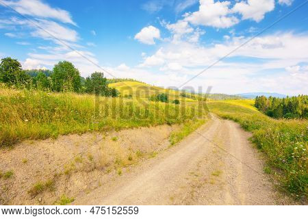 Lane Through Grassy Meadow. Green Hills Rolling In To The Distance. Blue Sky Above The Distant Mount