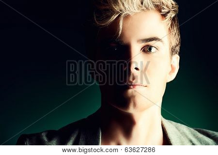 Close-up portrait of a modern handsome young man over dark background.