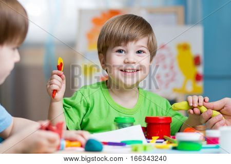 Children creativity. Kids sculpting from clay. Cute little boys mould from plasticine on table in kindergarten