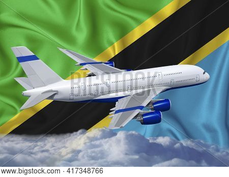 Tanzania Flag With White Airplane And Clouds. The Concept Of Tourist International Passenger Transpo