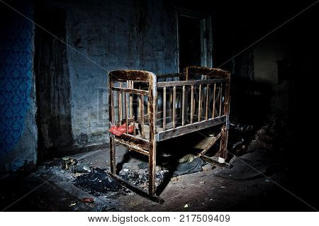 Old creepy eerie wooden baby crib in abandoned house. Horror concept.