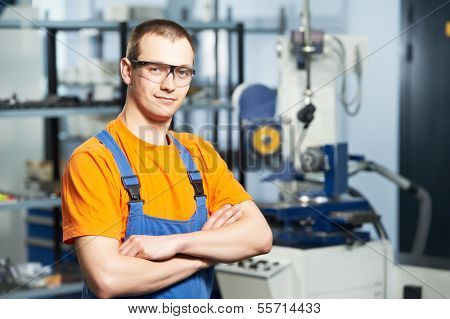 Portrait of young adult experienced industrial worker over industry machinery production line manufacturing workshop