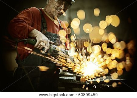 Industrial worker cutting and welding metal with many sharp sparks