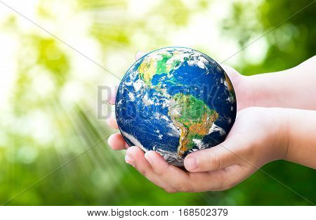 Planet in child hands on against green spring background. World Environment Day. World Mental Health Day concept.