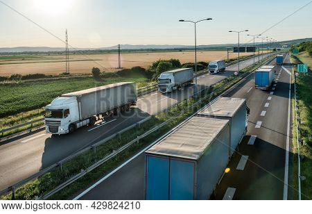 Transportation Trucks In Line Passing On A Highway On A Bright Blue Day. Highway Transit Transportat