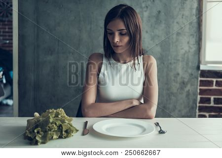 Young Woman Sitting On Chair With Salad On Table. Diet Concept. Weight Loss Problem. Starving Young 