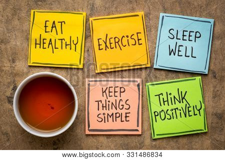 healthy lifestyle and wellbeing concept - a set of inspirational reminder notes with a cup of tea: eat healthy, exercise, seep well, keep things simple, think positively