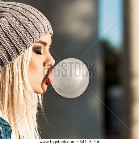 Beautiful Blonde Girl In Beanie Hat With Smokey Eye Make Up Who Enjoys Blows Big Bubble From Bubble