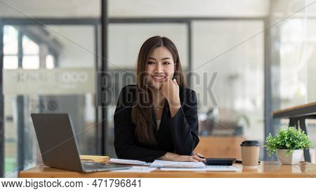 Asian Business Woman Using Calculator And Laptop For Doing Math Finance On An Office Desk, Tax, Repo