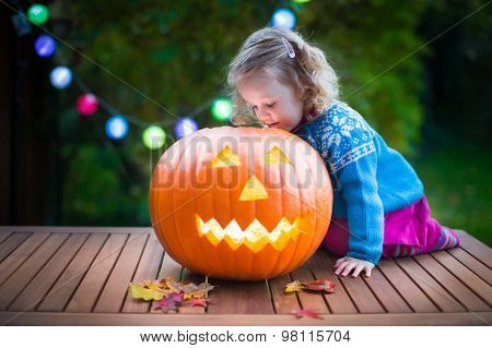 Little Girl Carving Pumpkin At Halloween