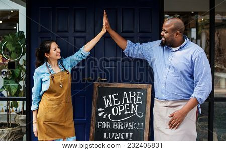 Cheerful business owners standing with open blackboard