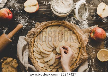 Cooking Apple Pie. Hands Adding Apple Slices To Pie Crust. Apple Pie Ingredients On Wooden Table