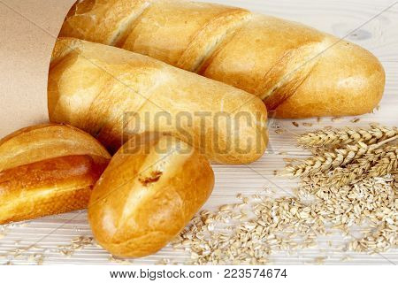 Whole bread on a light wooden surface. Baking with spikelets and corn on the table.