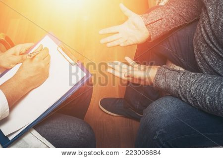 Psychologist listening to her patient and writing notes, mental health and counseling. Psychologist consulting and psychological therapy session concept, toned photo