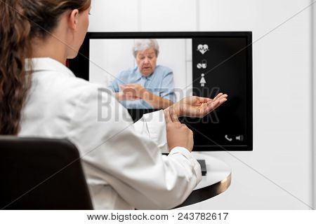 Doctor And Senior Woman Taking The Pulse Together, Telemedicine And Videotelephony For Medical Healt