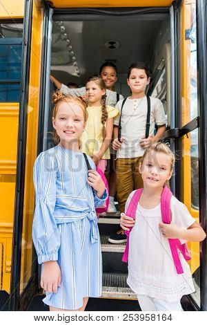 Group Of Adorable Schoolchildren Standing At School Bus