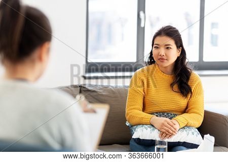 psychology and mental therapy concept - young asian woman patient and psychologist at psychotherapy session