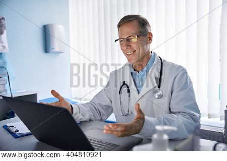 Happy Old Male Doctor Physician Talking, Consulting Patient Online By Webcam Video Call On Laptop Co